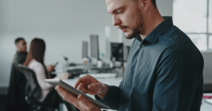 Photo of a person on a tablet checking measurements with office workers in the background.